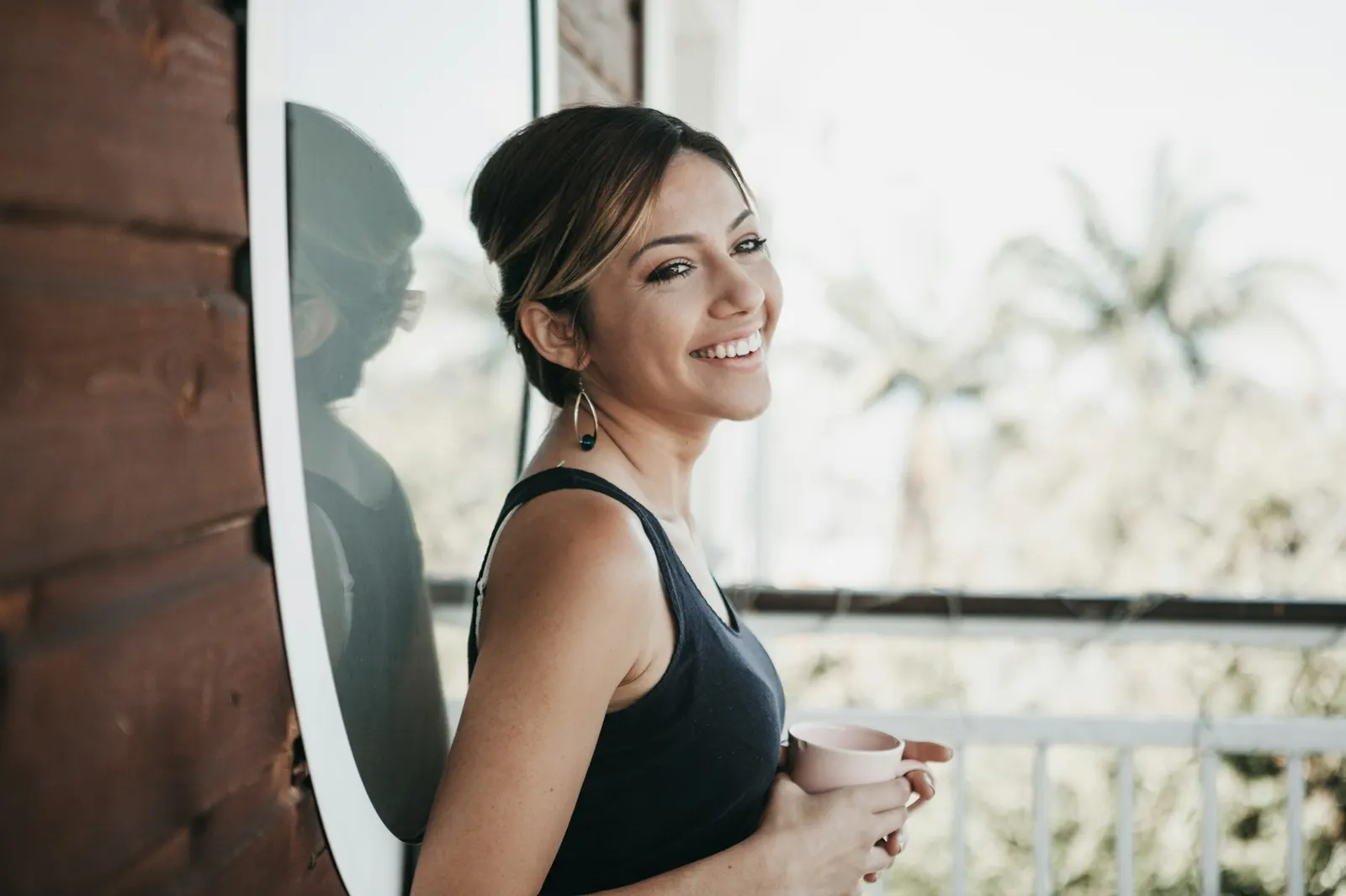 A person smiling by a bright window at home
