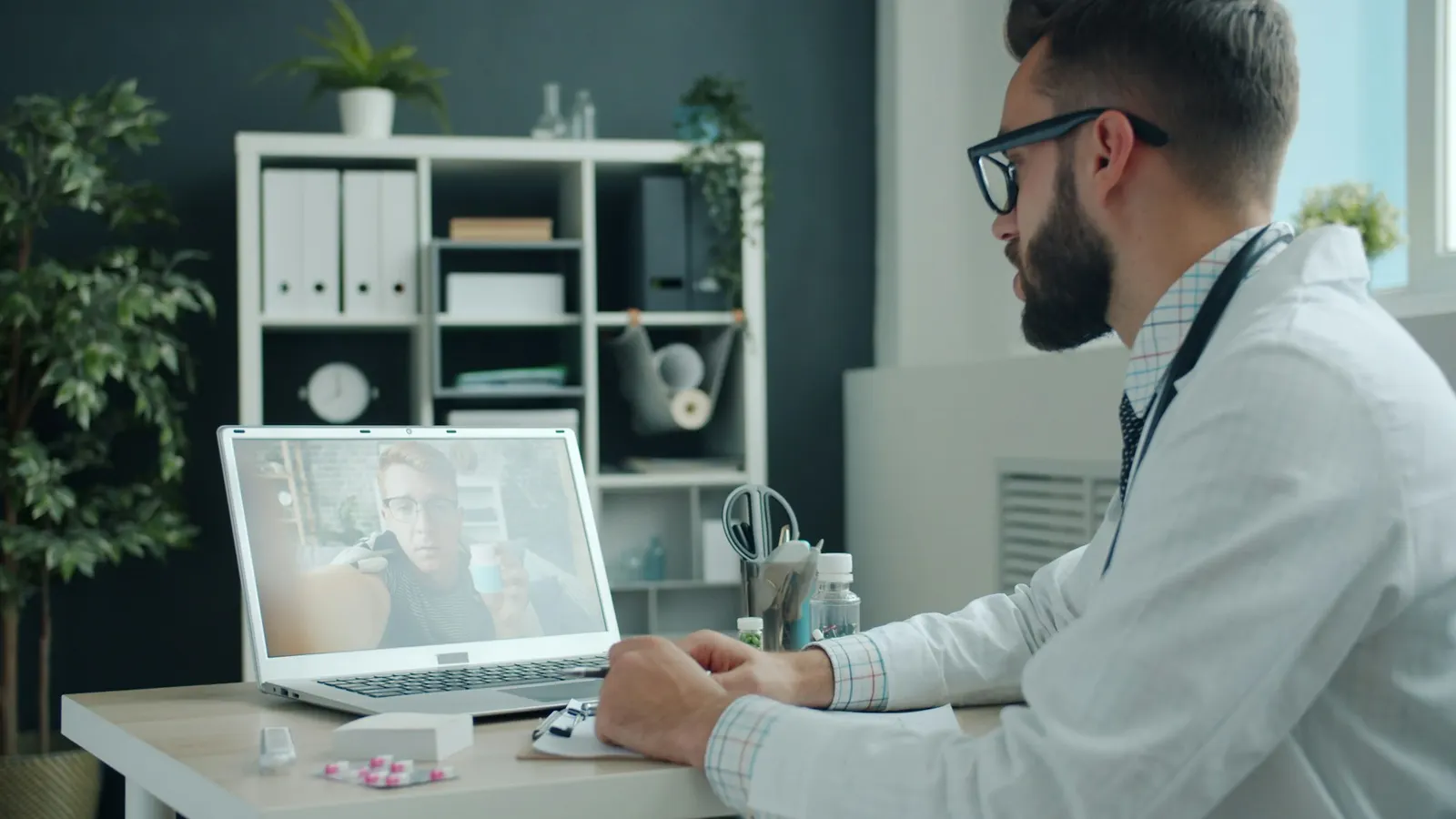 A physician reviewing a patient's case on a laptop during a video visit