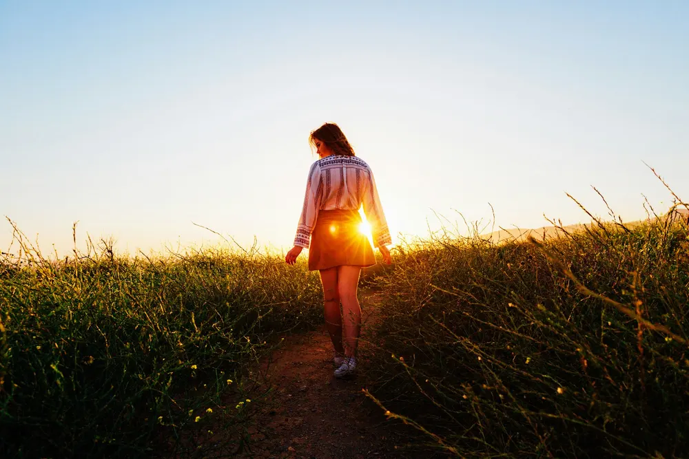A person walking along a grassy path in warm evening light